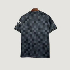 Maillot de foot noir à motif damier, manches courtes, vu de dos sur fond clair.