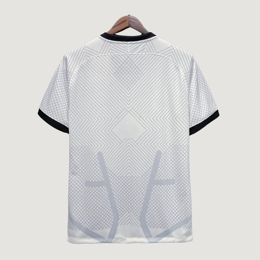 Dos d'un maillot de foot blanc avec motifs géométriques gris et manches à liseré noir.