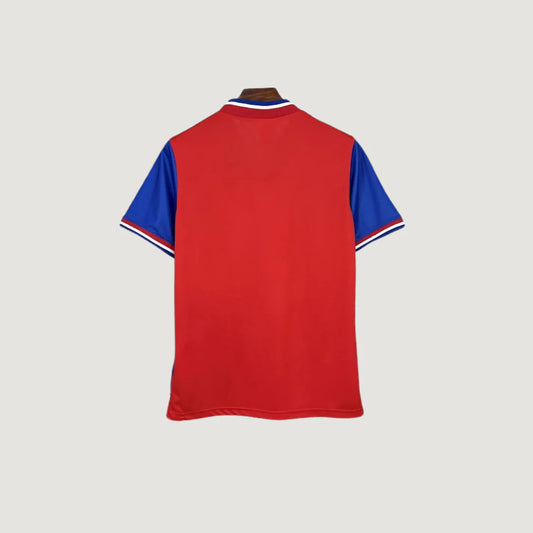 Dos d’un maillot de football rouge à manches courtes bleues, col style sportif.