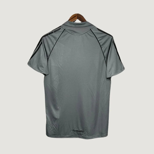 Dos d’un maillot de foot gris avec bandes noires sur les épaules, style sportif.
