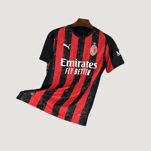 Maillot de foot AC Milan noir et rouge, logos Puma et Emirates visibles, fond uni.