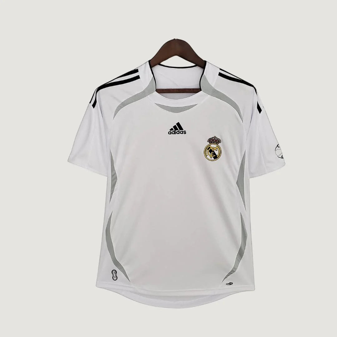 Maillot de foot blanc manches courtes avec logo, détails gris et motif sur épaule, suspendu