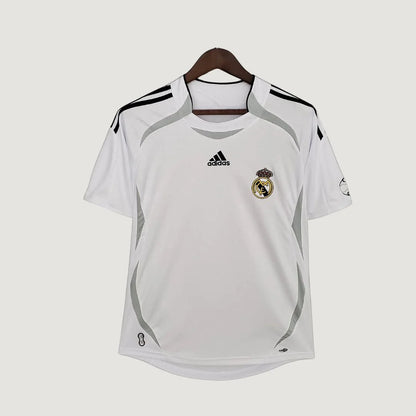 Maillot de foot blanc manches courtes avec logo, détails gris et motif sur épaule, suspendu