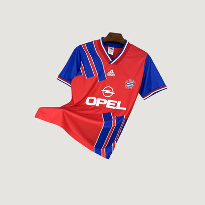 Maillot de foot rétro rouge et bleu à manches courtes, logo Adidas et sponsor Opel visible.
