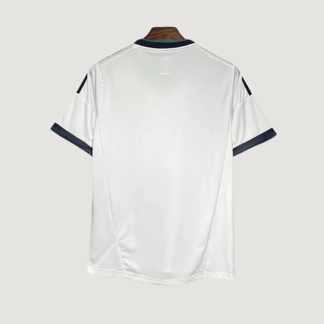 Dos d’un maillot de football blanc à manches courtes, liserés noirs, sur fond uni.