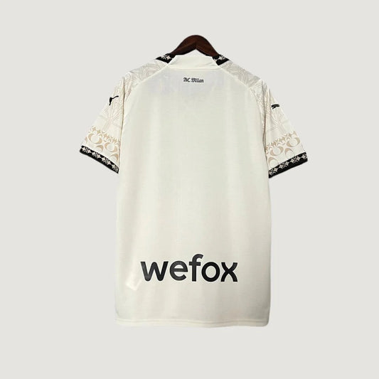 Maillot de foot blanc dos, manches motifs beige, texte AC Milan et sponsor wefox visible.