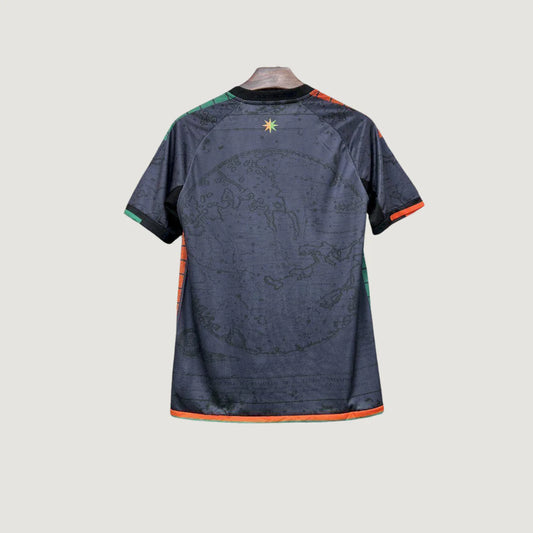 Maillot de foot noir motif globe, détails verts et orange, vu de dos, style moderne.