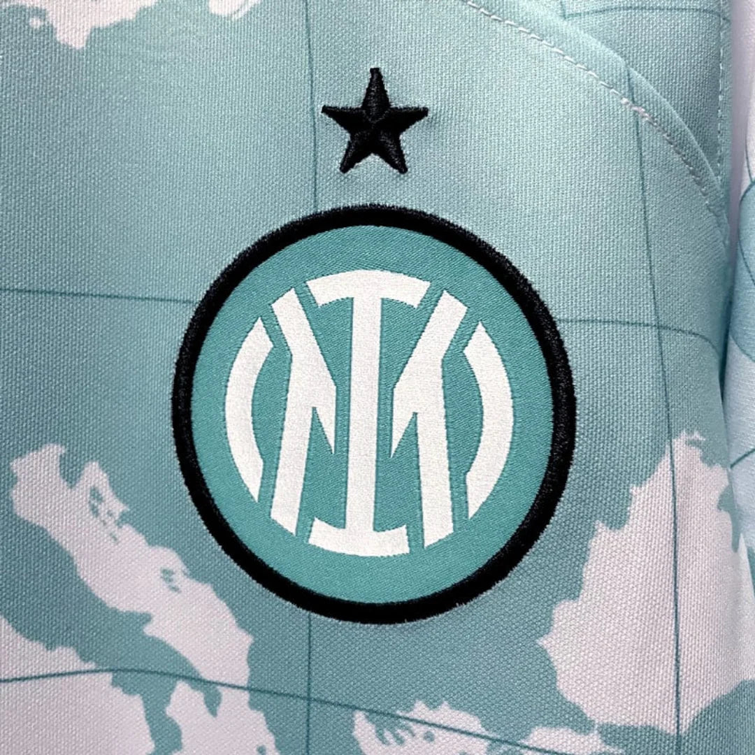 Détail du maillot de foot bleu avec blason rond et étoile noire sur fond imprimé carte