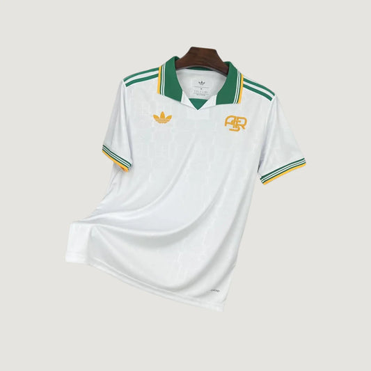 Maillot de foot blanc à col vert, détails jaunes et verts, style rétro, manches courtes.