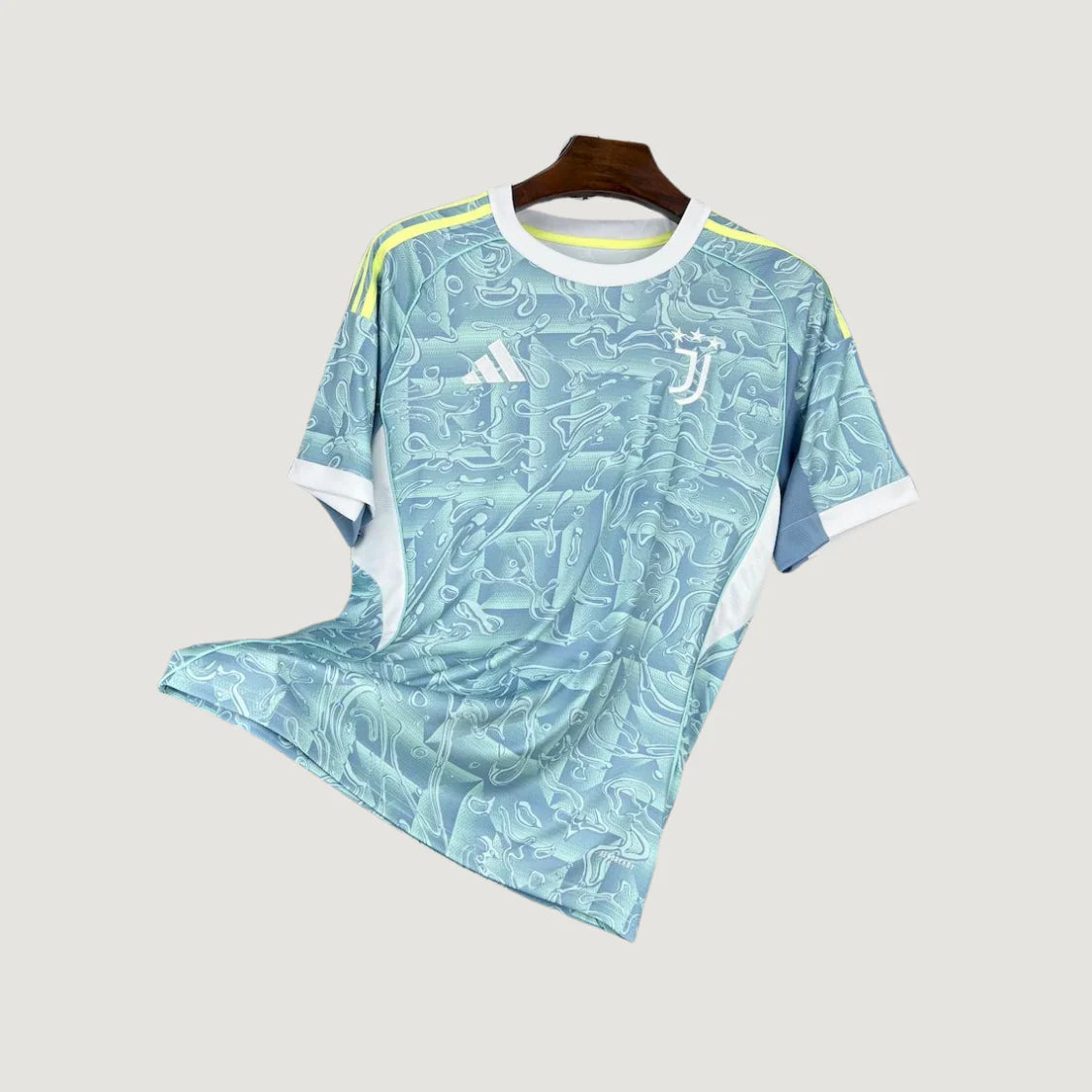Maillot de foot bleu clair motif abstrait, logo Juventus, bords blancs, bandes jaunes sur épaules.