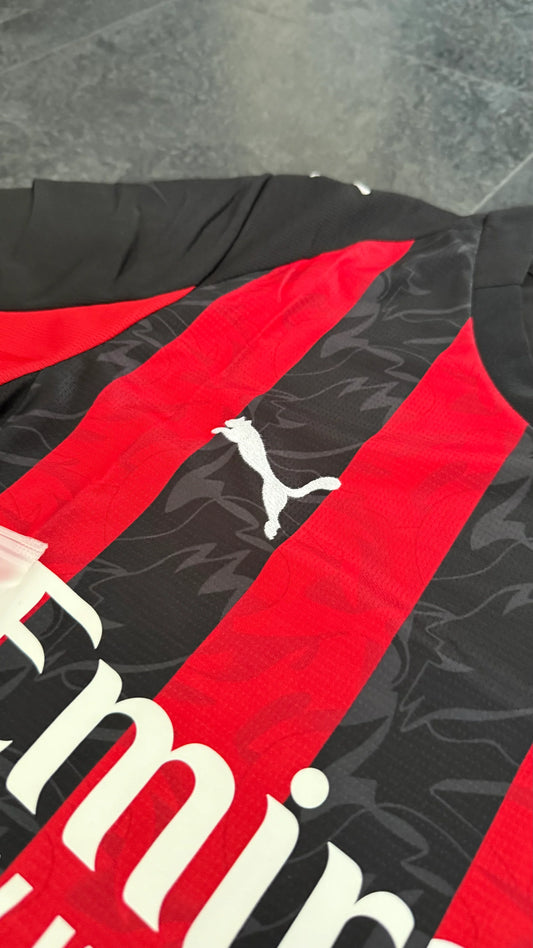Détail d’un maillot de football rouge et noir avec logo Puma, motif abstrait.