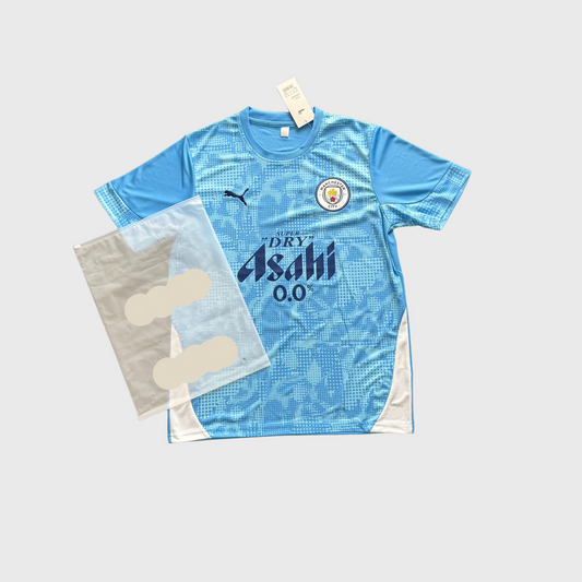 Maillot de foot bleu manches courtes avec écusson et sponsor, emballage à côté.