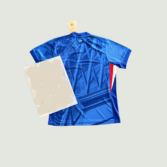 Maillot de foot bleu motif graphique vu de dos, détails rouges et blancs sur le côté.
