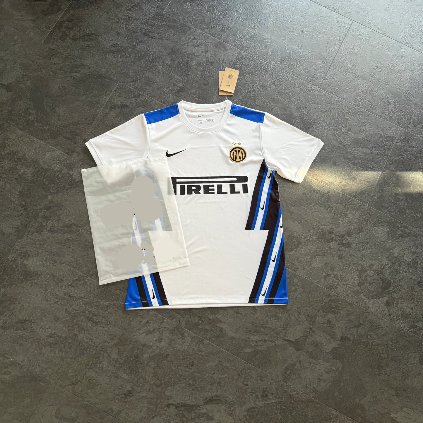 Maillot de foot blanc Inter Milan avec logo Nike, motif bleu et noir, posé au sol