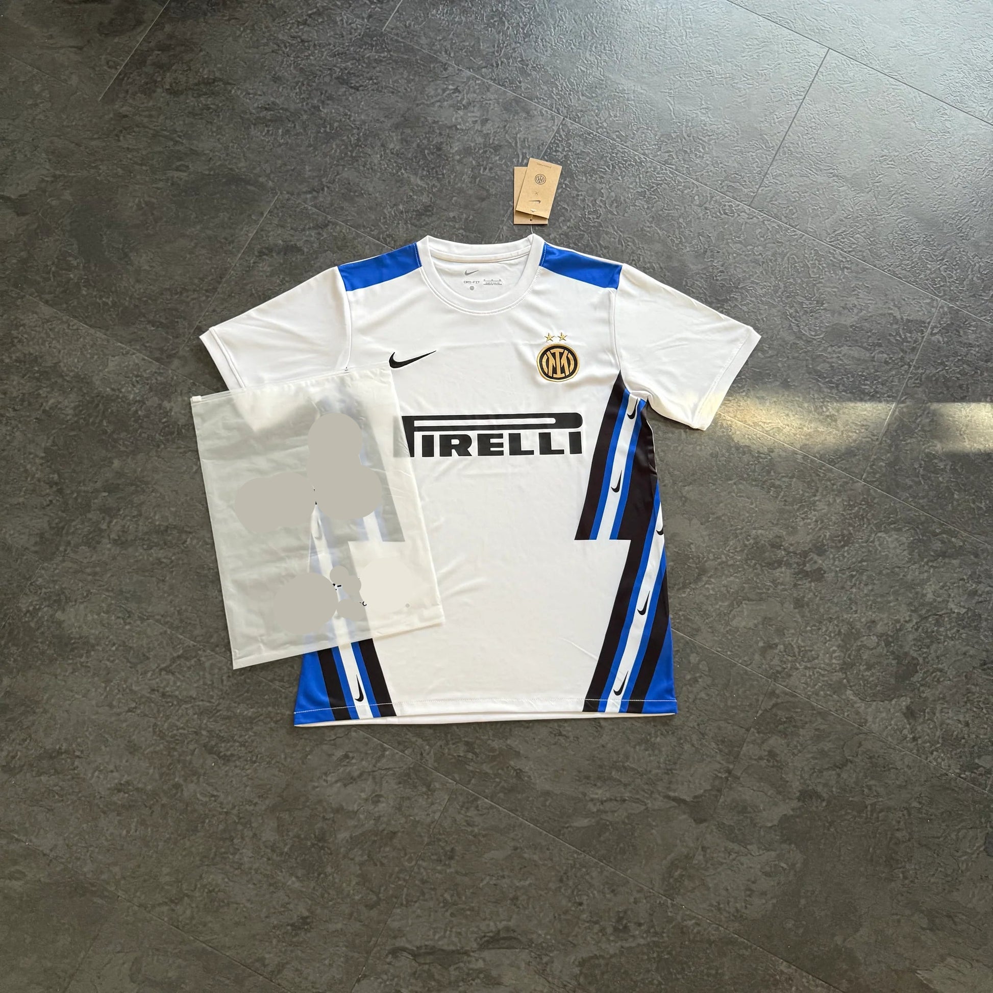 Maillot de foot blanc Inter Milan avec logo Nike, motif bleu et noir, posé au sol