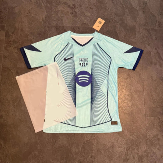 Maillot de foot bleu clair avec motifs géométriques et logo du club brodé sur la poitrine.