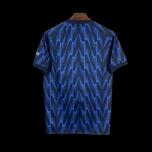 Maillot de foot bleu et noir motif zigzag, manches courtes, dos visible sur cintre